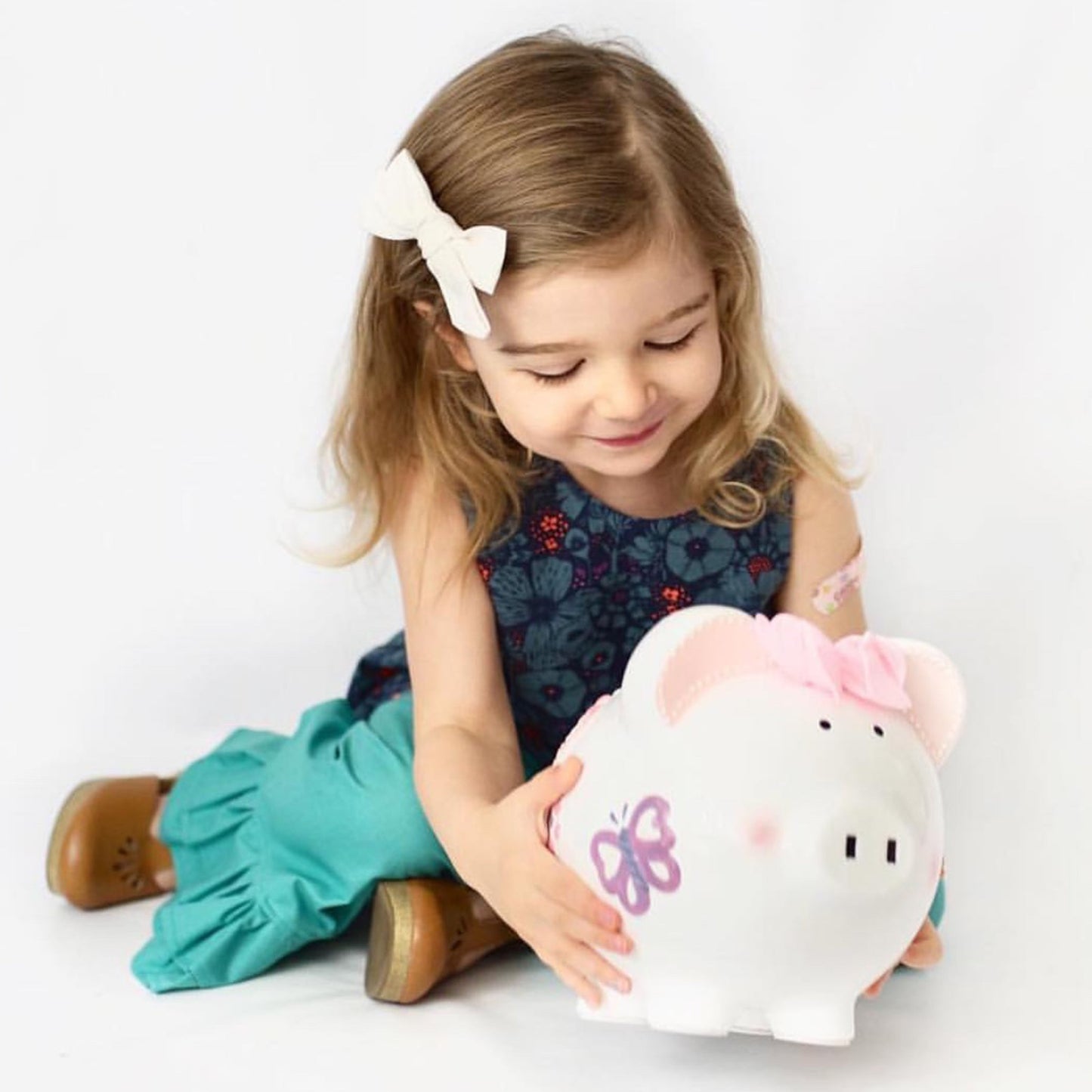 Happy child holding and smiling at the handpainted butterfly piggy bank
