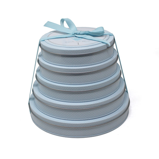 Stacked blue circular tins with handprint keepsake kits tied with a blue ribbon