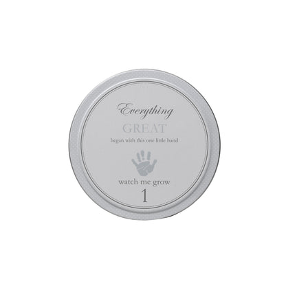 Close up of smallest gray tin labeled watch me grow 1 with handprint design