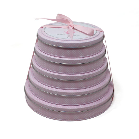 Stack of five pink polka-dot round tins tied with a pink ribbon