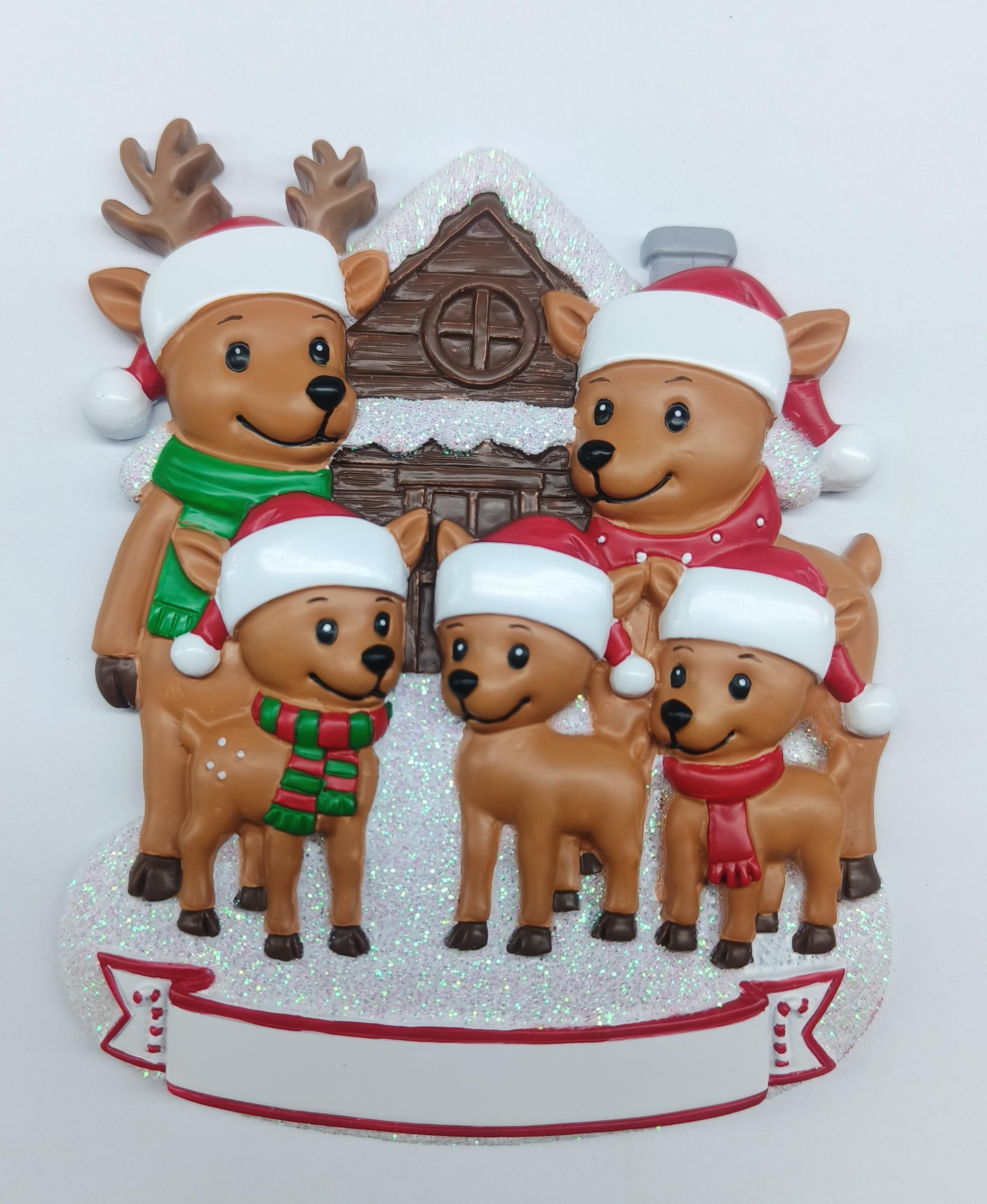 Handpainted reindeer family ornament of five with Santa hats and scarves in front of snowy house with glitter accents