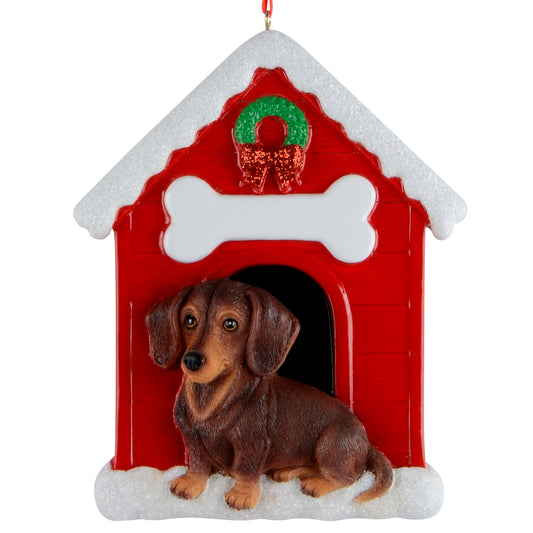 Handpainted brown dachshund sitting in front of red doghouse ornament with snowy roof and Christmas wreath