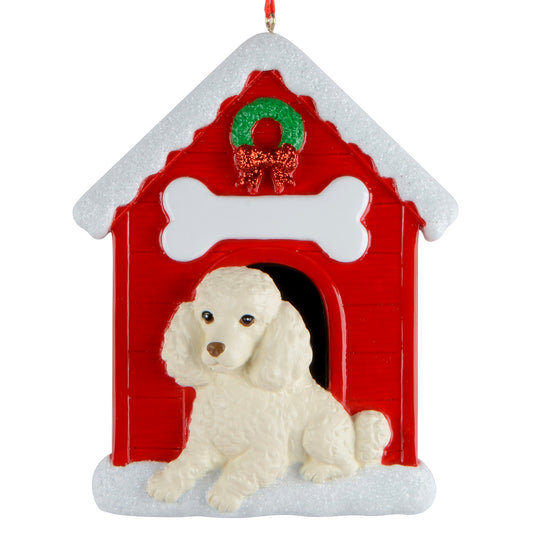 Holiday ornament featuring a white poodle sitting in front of a red doghouse decorated with a green wreath and snowy roof