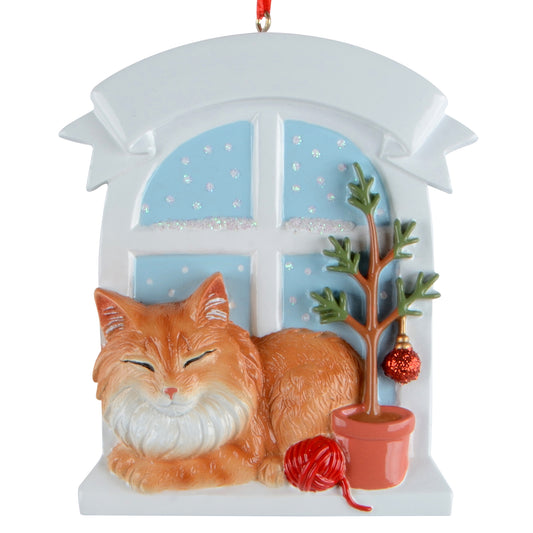 Brown Maine Coon Cat ornament resting by a snowy window with Christmas tree and red ball of yarn