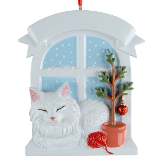 Handpainted ornament of a white Persian cat resting by window with small tree and red yarn ball