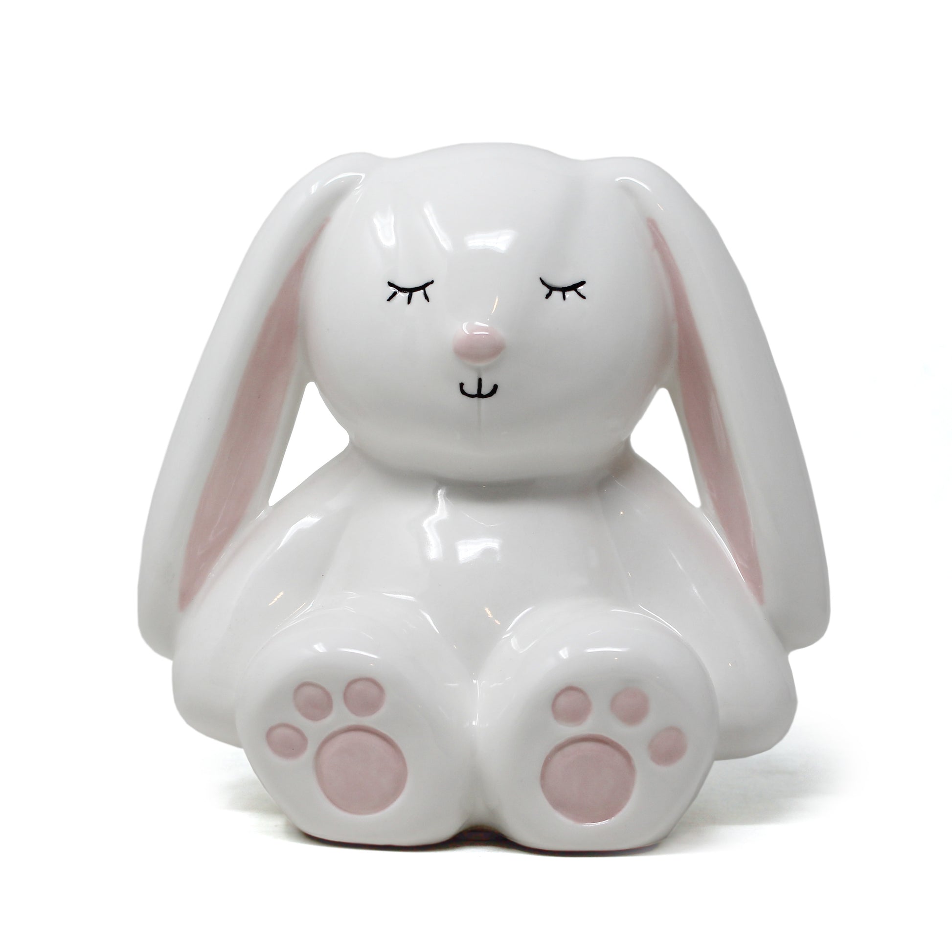 White ceramic bunny piggy bank with pink ears and paw pads and closed eyes