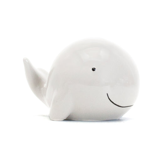 Side view of glossy white ceramic whale piggy bank with black eyes and smile