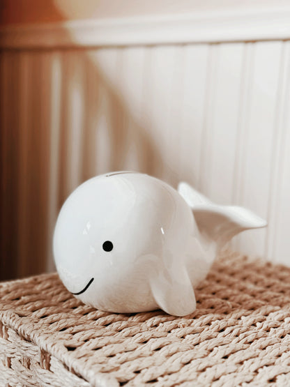 White whale piggy bank displayed on woven basket in cozy room setting