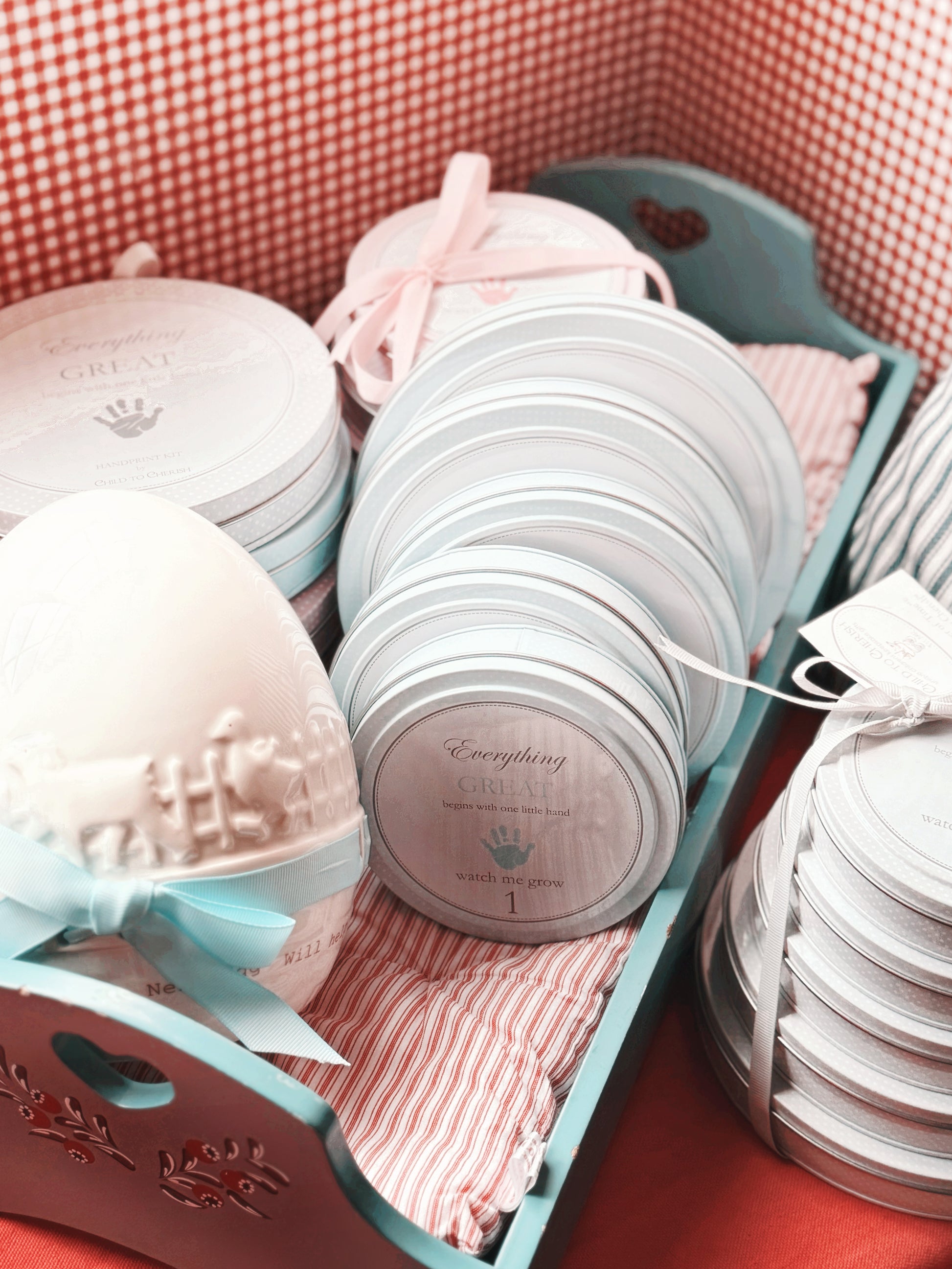 Blue handprint keepsake tins displayed in a vintage-style wooden tray with striped fabric