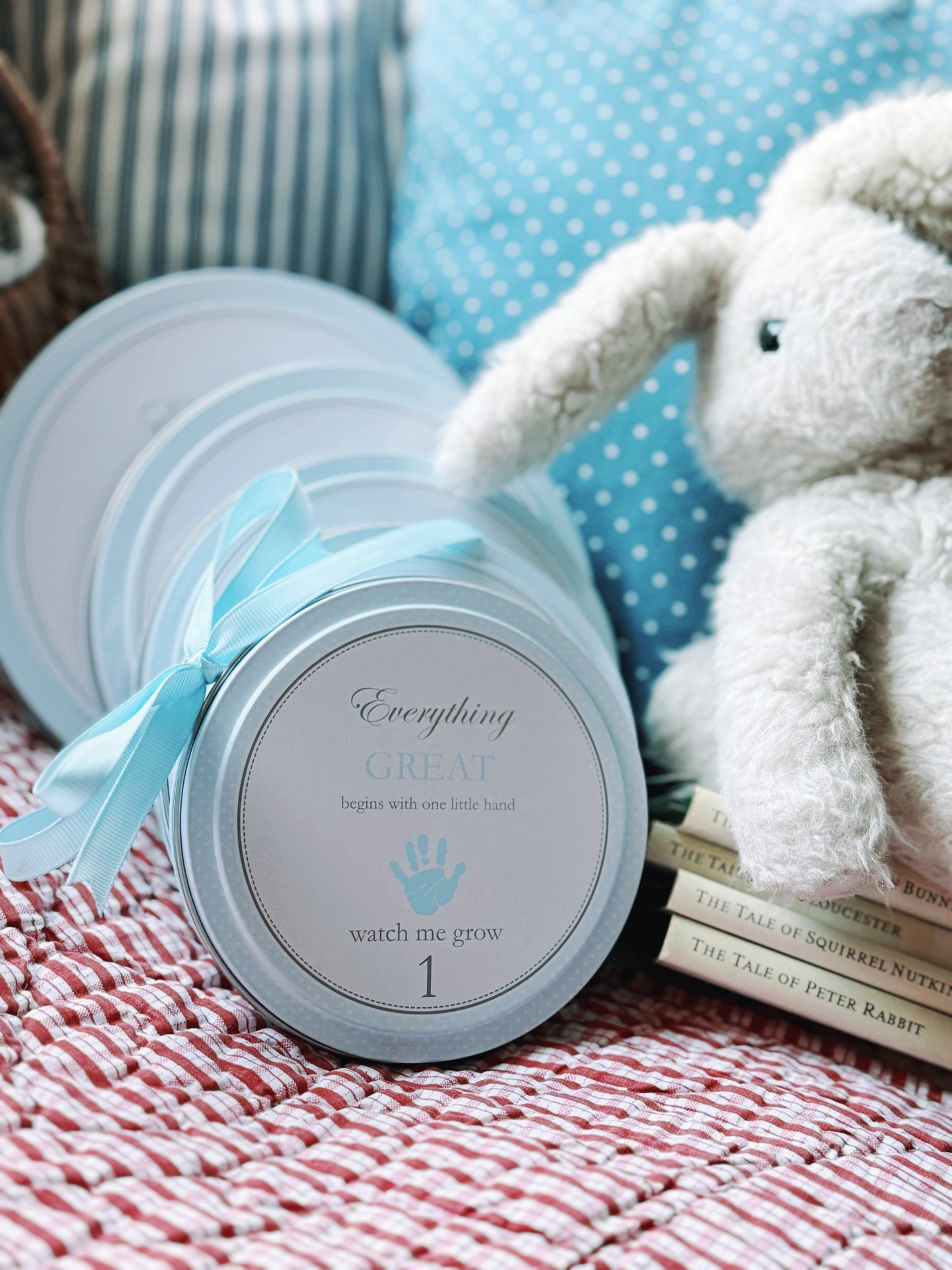 Multiple blue handprint kit tins arranged on a striped cloth with a white ceramic egg nearby