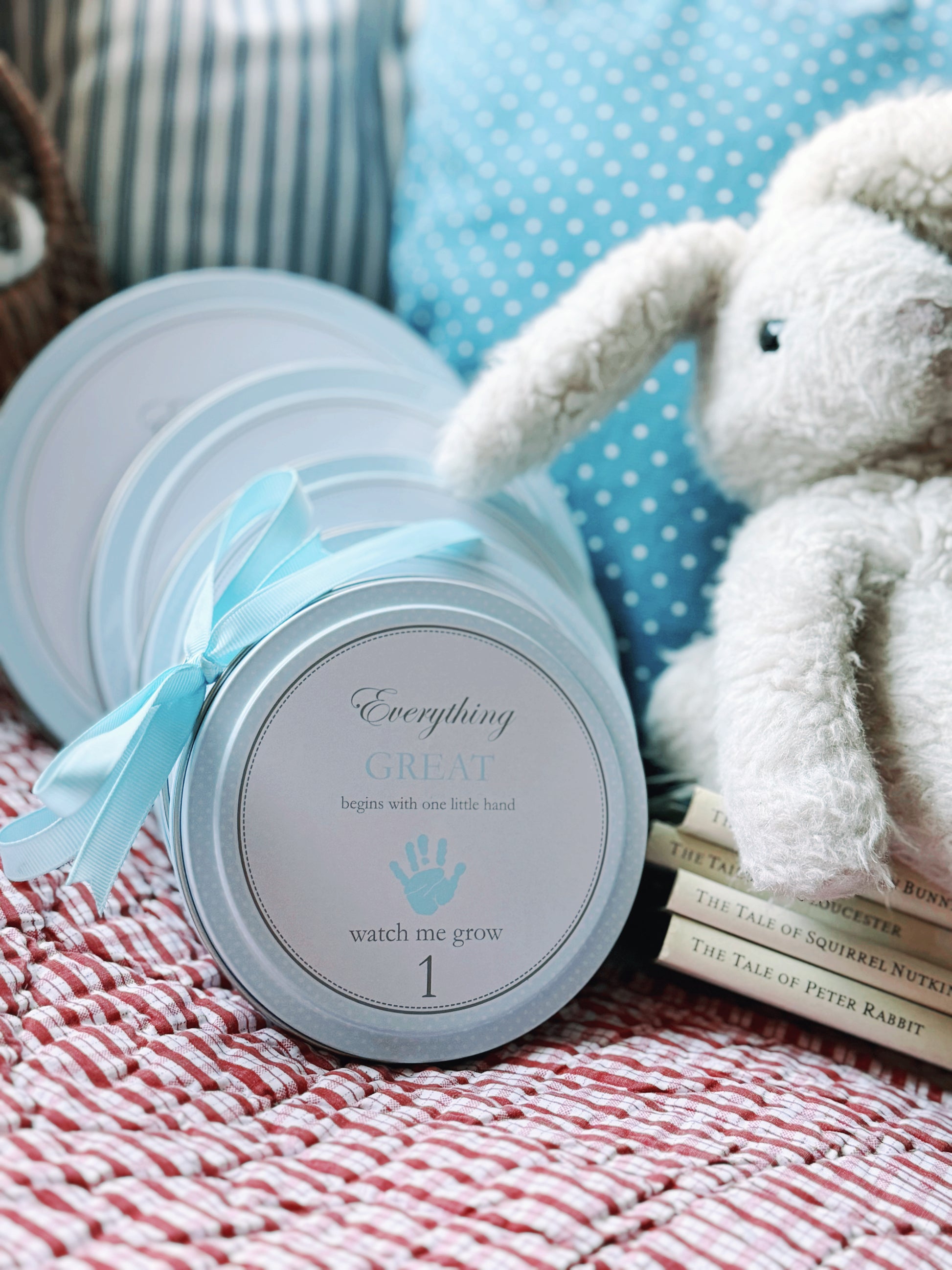 Multiple blue handprint kit tins arranged on a striped cloth with a white ceramic egg nearby