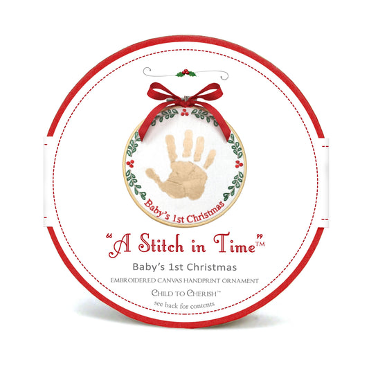 Packaging of A Stitch in Time Baby's 1st Christmas handprint ornament showing wood hoop and embroidered canvas with gold handprint and red ribbon