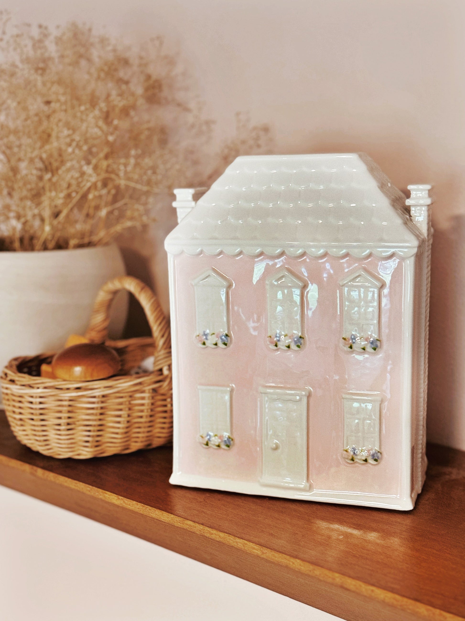 Dolly’s House piggy bank displayed on wooden shelf with basket and decor items in background