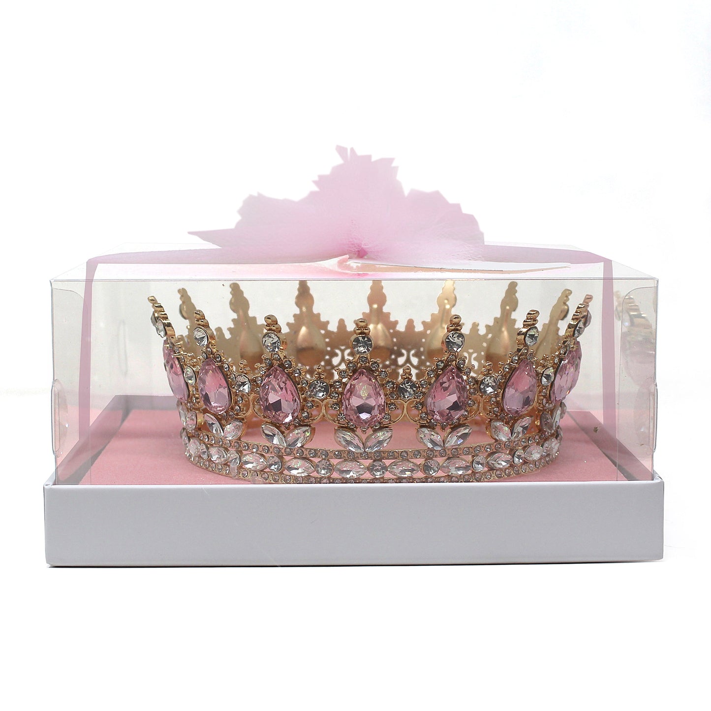 Golden crown adorned with large pink teardrop rhinestones and clear rhinestones inside a clear display box with pink base and tulle ribbon