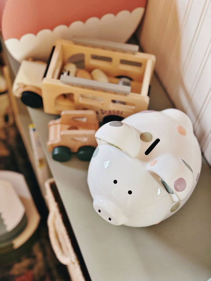 Close-up of piggy bank displayed on a home shelf with other decor items