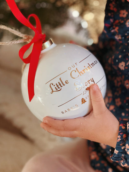 Close-up of child holding the porcelain ornament with gold text and red ribbon
