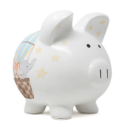 Side view of white ceramic piggy bank with painted hot air balloon carrying animals and stars