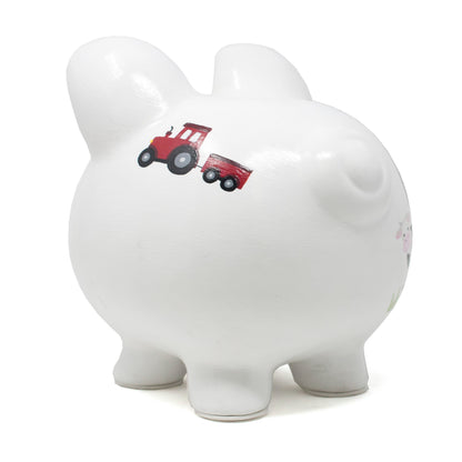 Side view of white ceramic piggy bank with handpainted red tractor and barnyard scenes