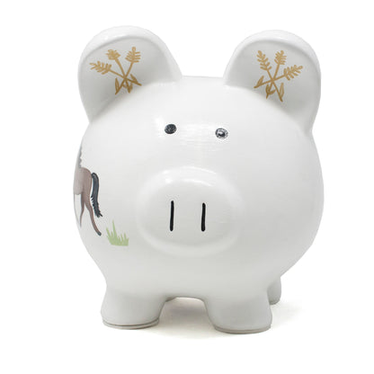 Front view of white ceramic piggy bank showing simple black eyes and snout, with ears decorated with gold wheat motifs