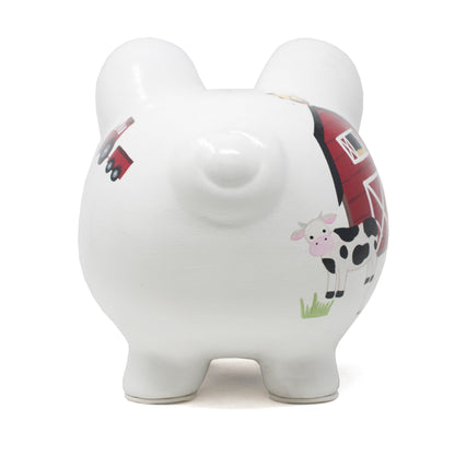 Back view of white ceramic piggy bank featuring painted cow and tractor designs