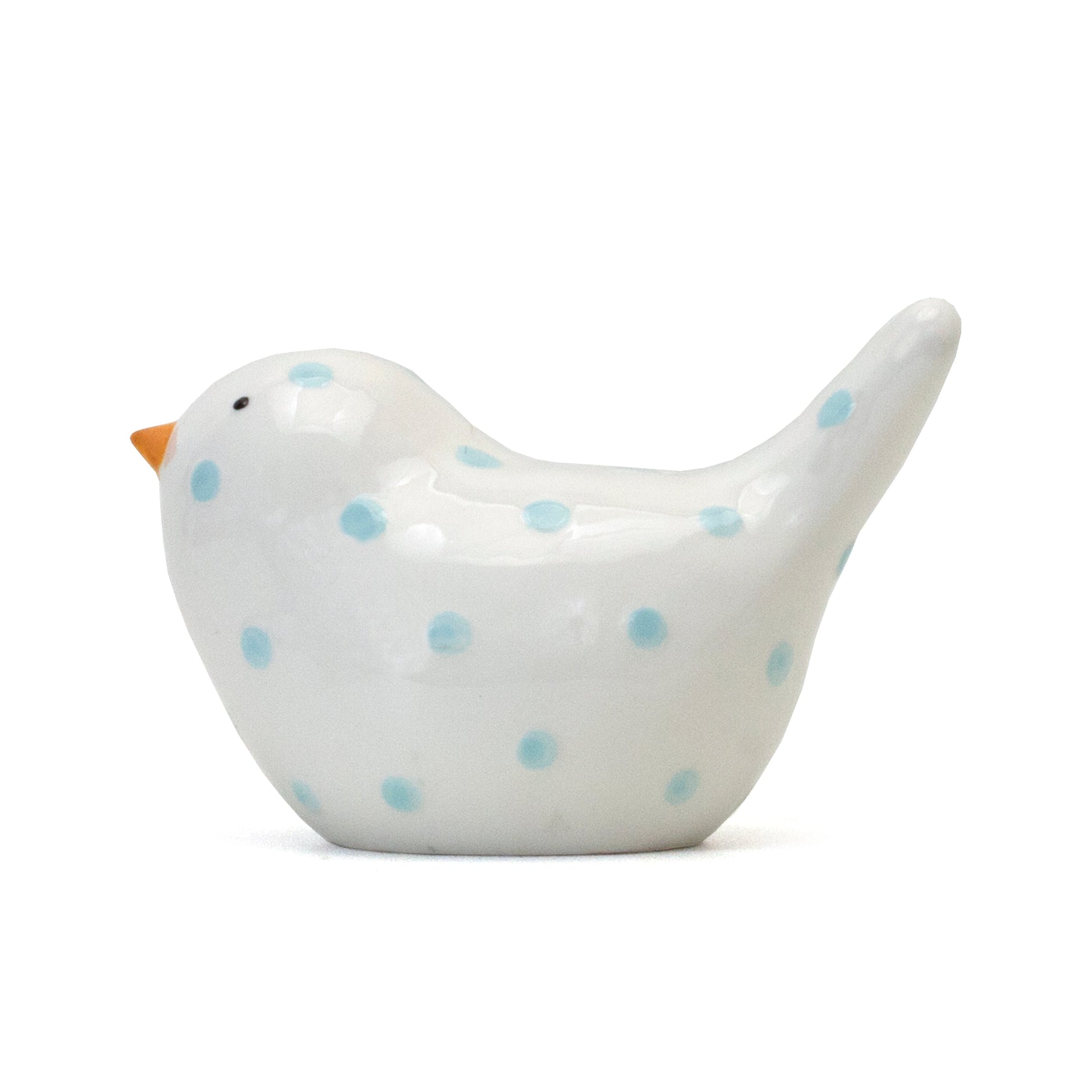 Opposite side view of glossy white bird bank with blue polka dots and small orange beak