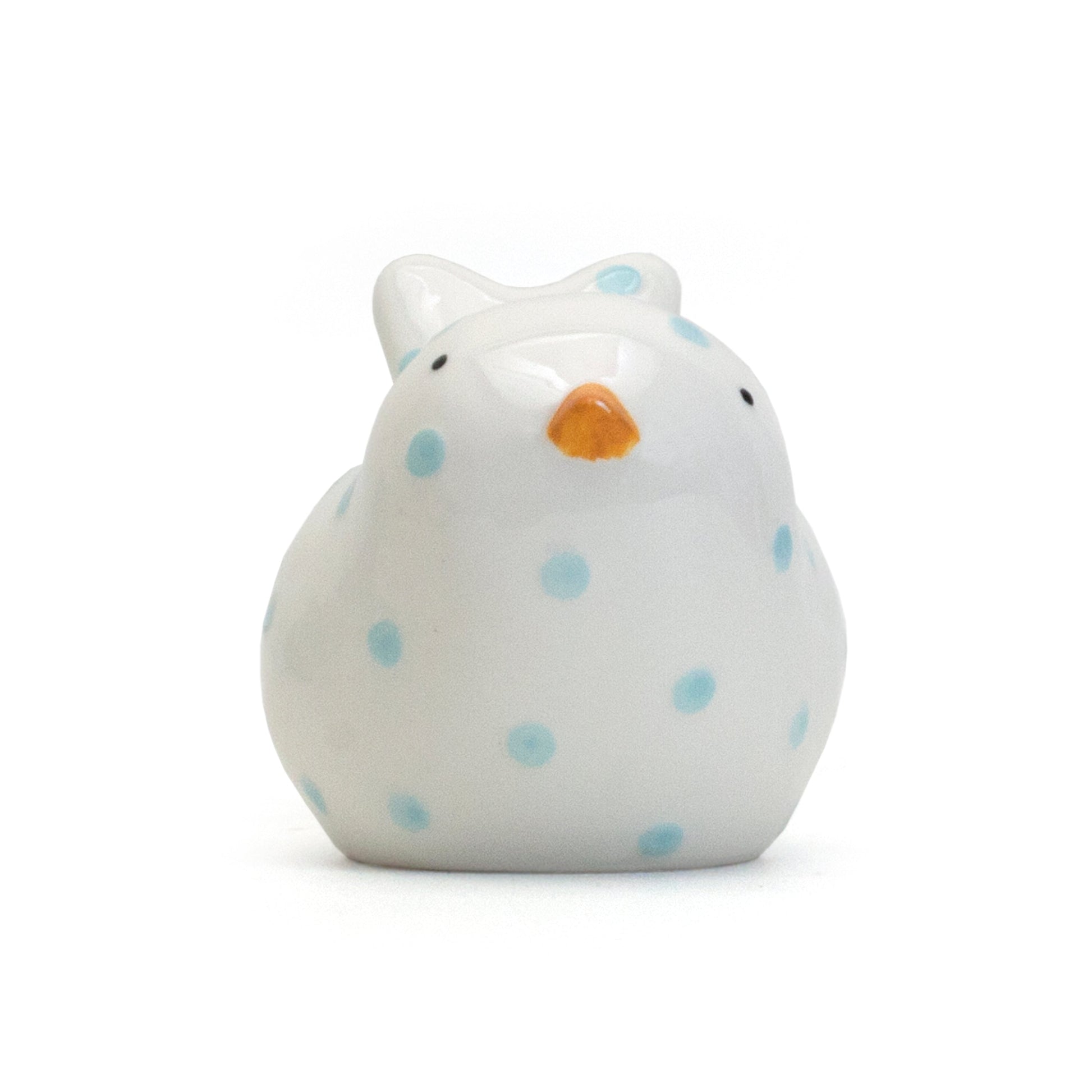 Front view of white bird-shaped piggy bank with blue polka dots and tiny orange beak