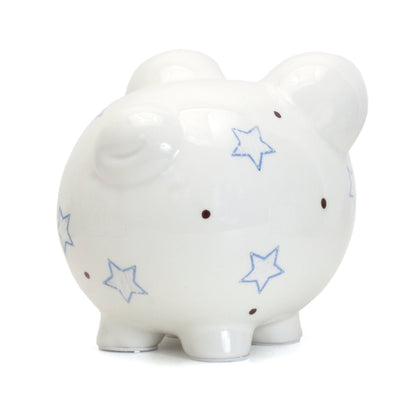 Left angled back view of white ceramic piggy bank featuring blue star patterns and brown dots