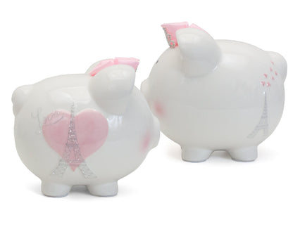 Two white ceramic piggy banks side by side showing front with pink heart and Eiffel Tower and back with Eiffel Tower and hearts designs