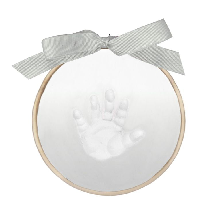Close-up of white clay handprint impression in wooden ring frame with grey ribbon bow