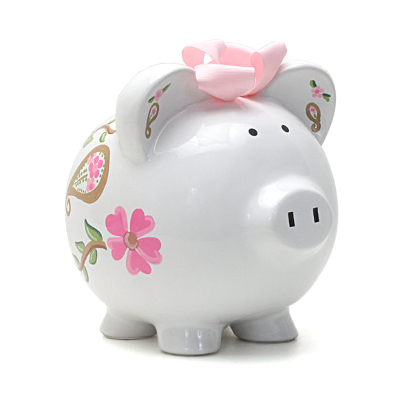White ceramic piggy bank with pink paisley and floral designs and pink ribbon bow on top, front side view