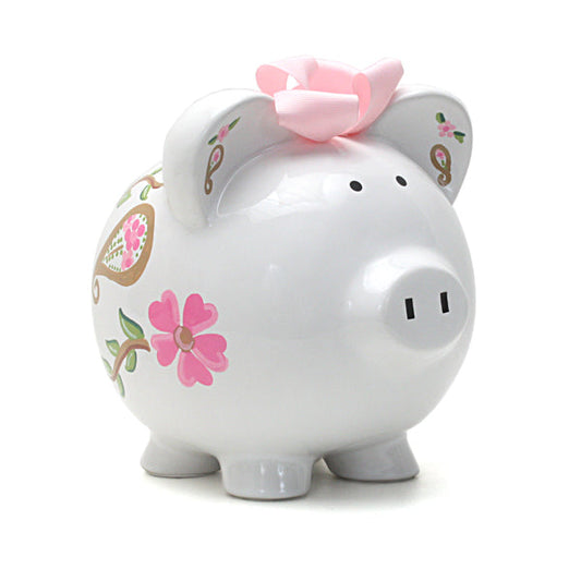 White ceramic piggy bank with pink paisley and floral designs and pink ribbon bow on top, front side view