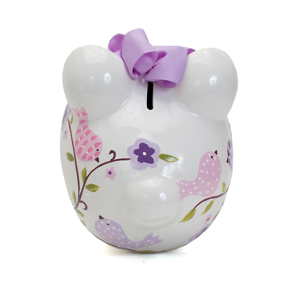 Top view showing coin slot on back of ceramic piggy bank adorned with purple bow and bird designs