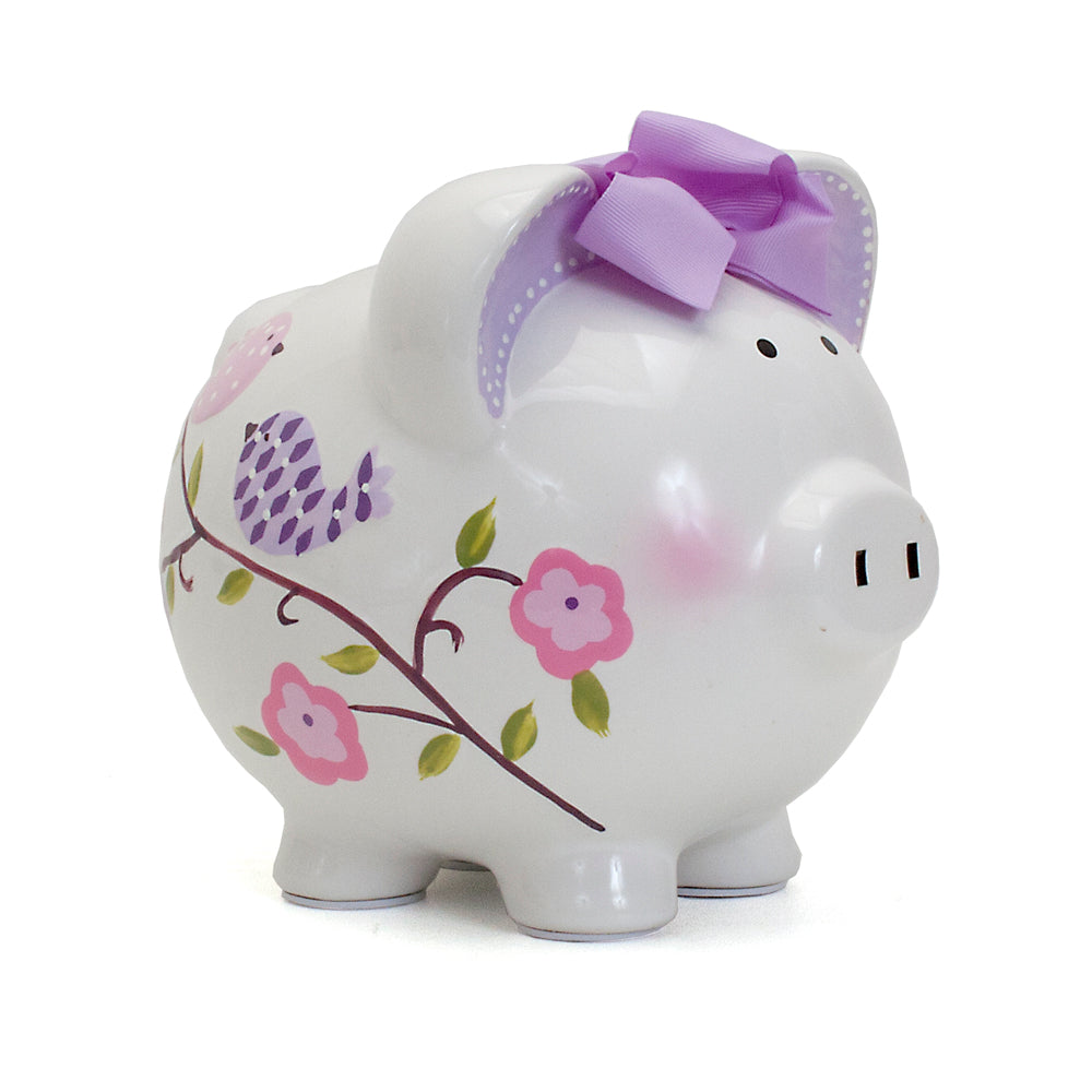 Side view of handpainted ceramic piggy bank with purple bow and bird floral design