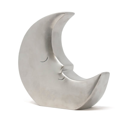 Silver metallic crescent moon shaped piggy bank with a calm face, angled left view