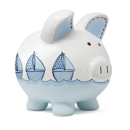 Front side view of white ceramic piggy bank with three blue handpainted sailboats and light blue waves