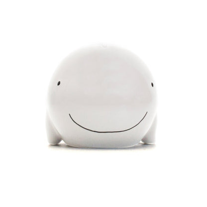 front view of white ceramic whale piggy bank with small eyes and smile